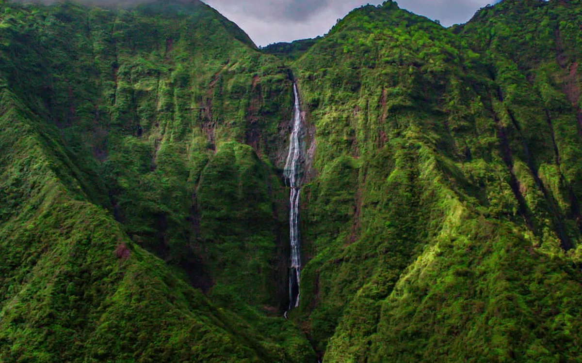 A helicopter lifting off over Kauai in early morning light