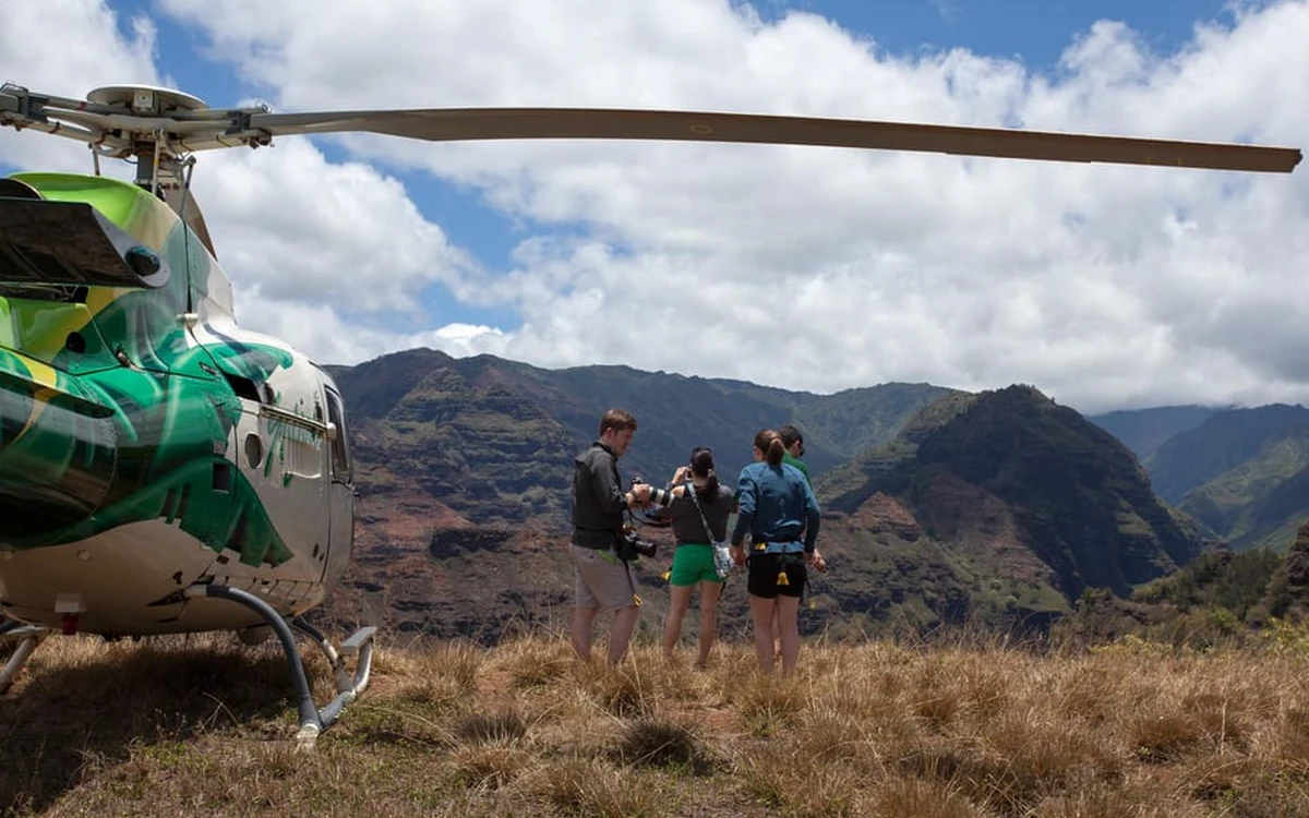 A helicopter and its rotor wash over a landing pad on Kauai