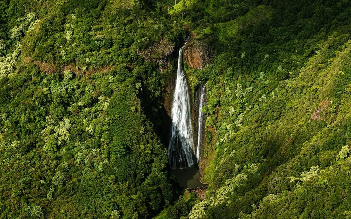 A helicopter over the coastline of Kauai at golden hour