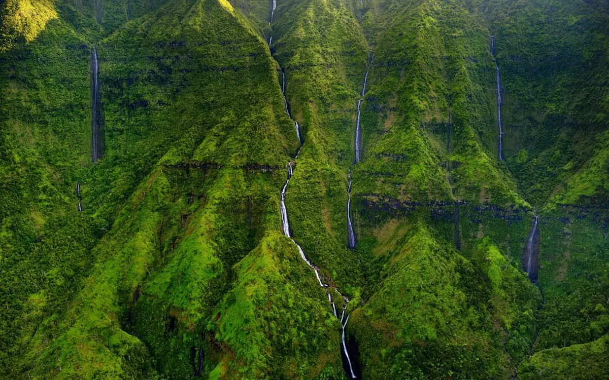 A helicopter passing a waterfall on Kauai&rsquo;s waterfall safari route